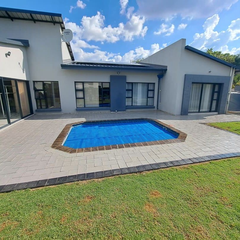 a pool surrounded by light grey paving at a modern house