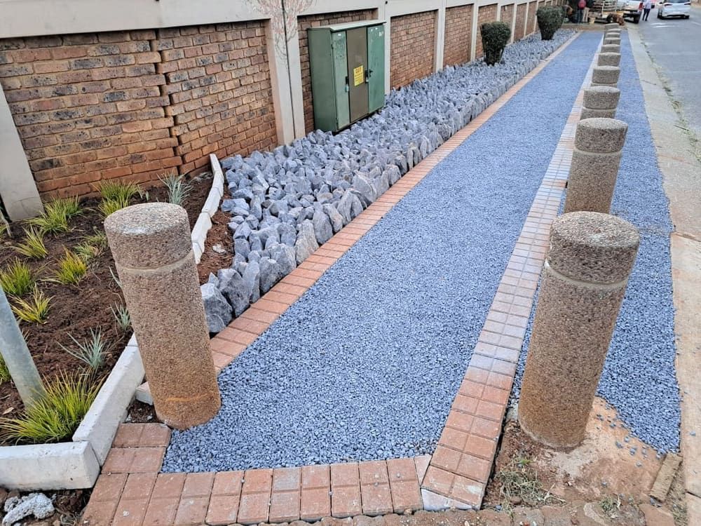 gravel path edged in red pavers between concrete bollards