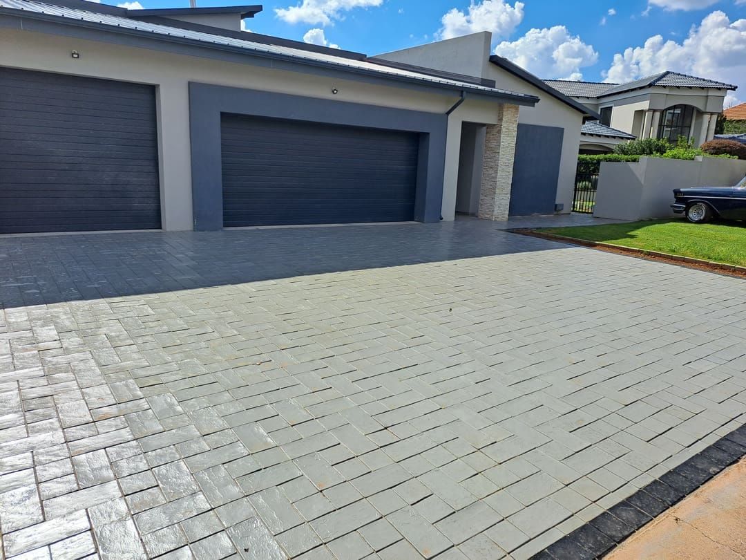 grey paver driveway at a house with dark garage doors