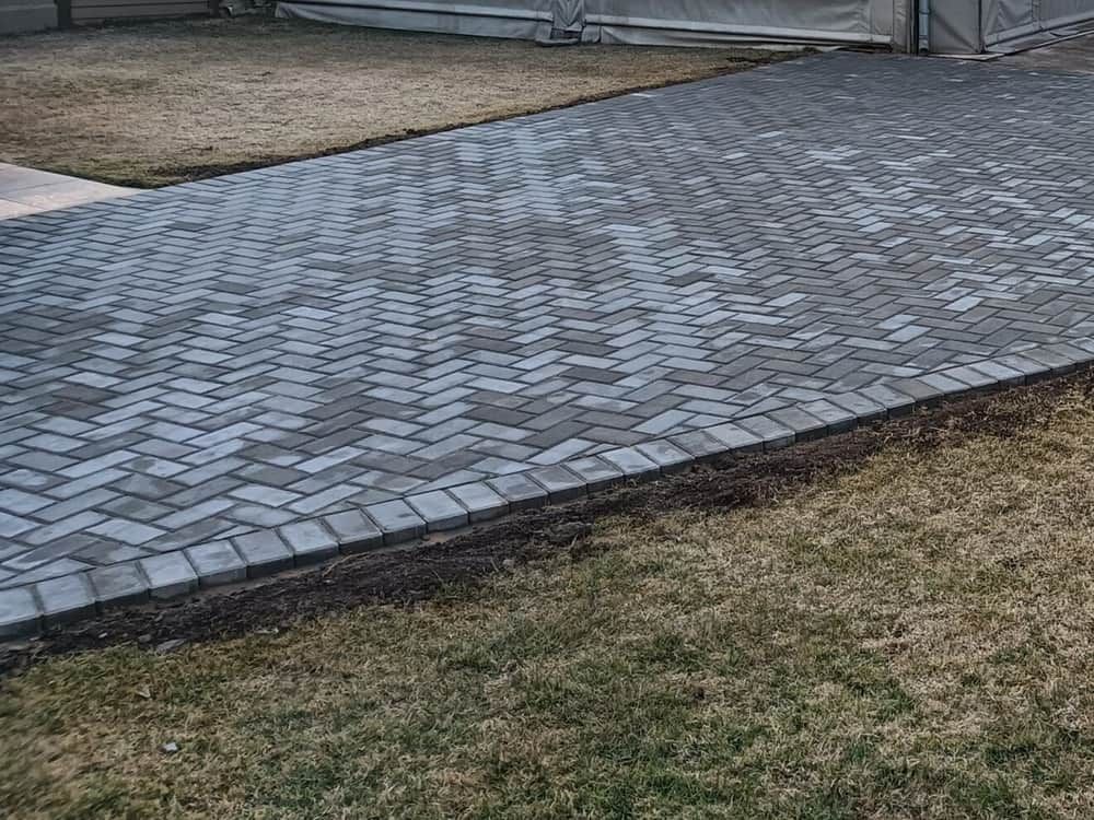grey herringbone paving beside a lawn